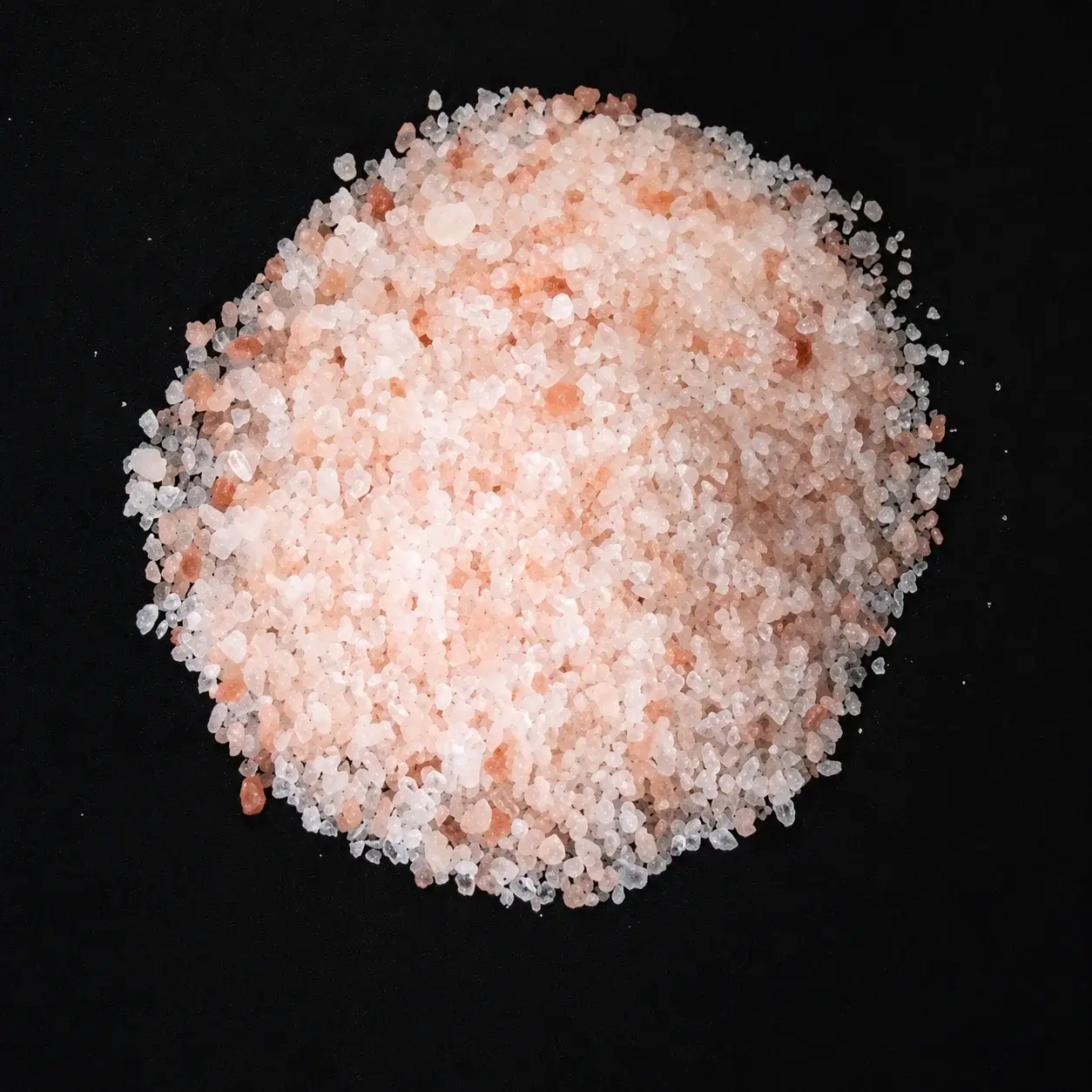Himalayan pink salt granules on a black background