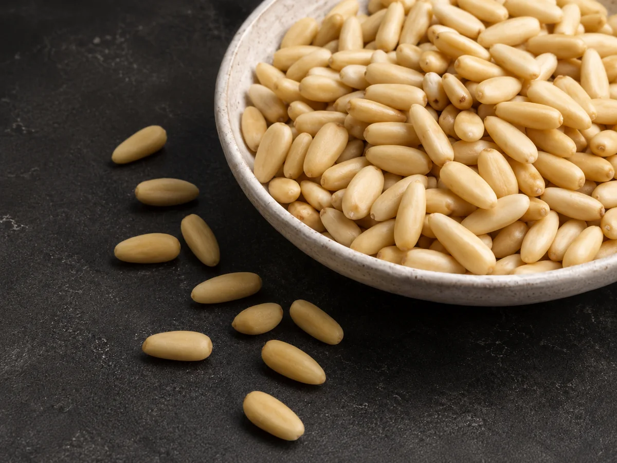 Premium Afghan Chilgoza pine nuts in a white ceramic bowl on a dark background